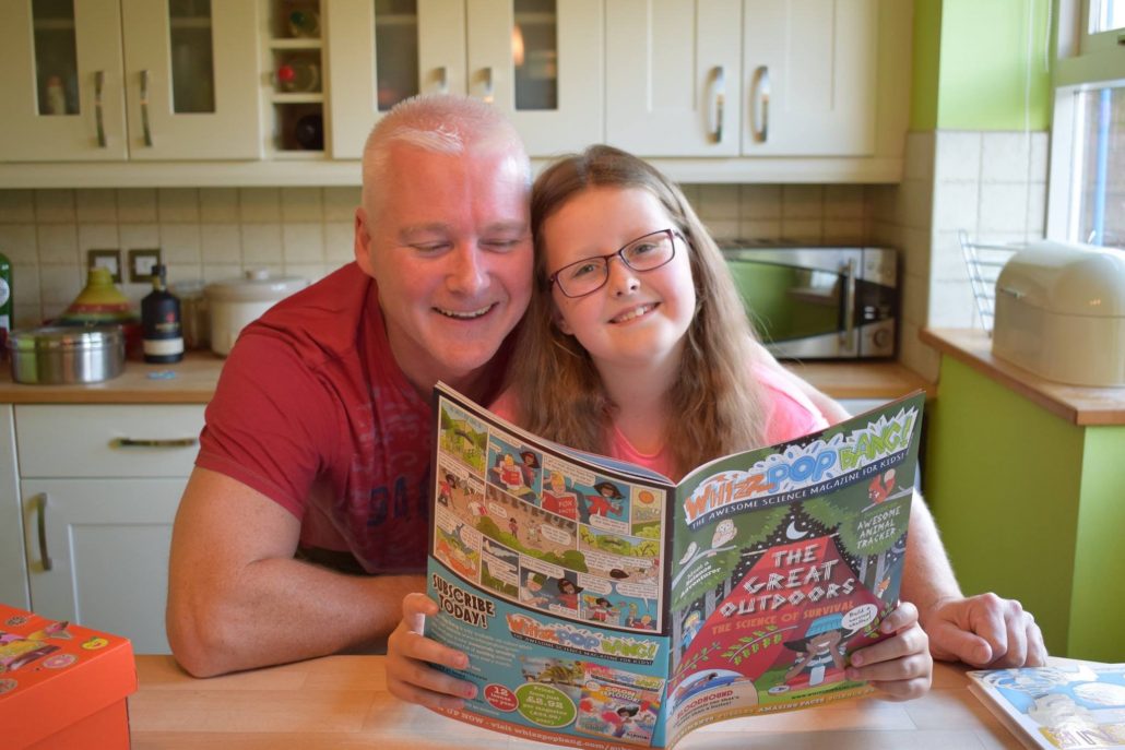 Father with daughter reading Whizz Pop Bang science magazine