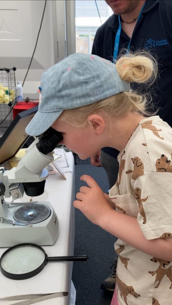 A young girl looks into a microscope at Cheltenham Science Festival