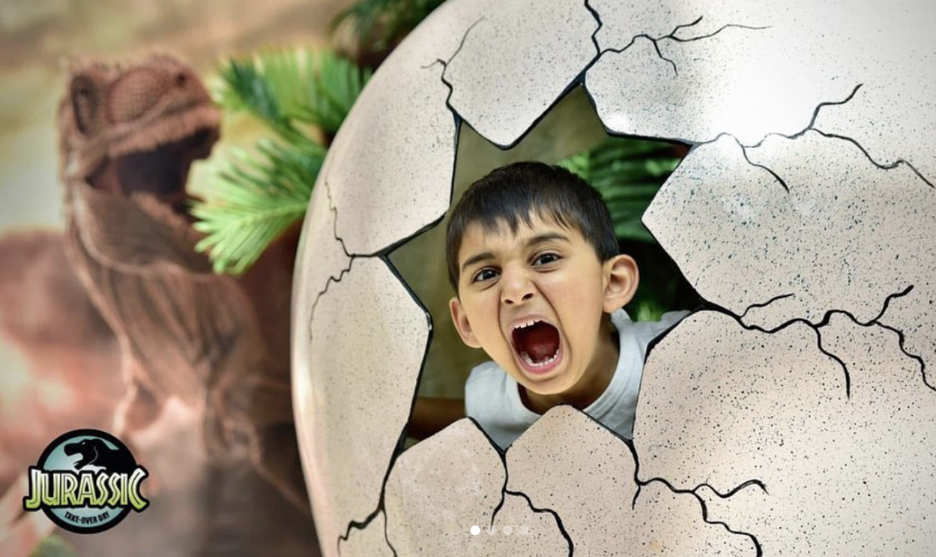 A boy bursts out of a dinosaur egg prop